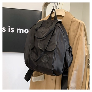 Detail of a black multi-pocket backpack with logo and drawstring side pockets on a hanger