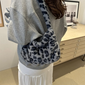 Blue-grey leopard print faux fur hobo bag worn by model in a minimalist home setting