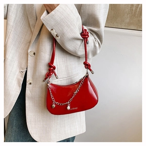 Detail of red crescent bag with knotted handle, silver heart chain, and pearl charms