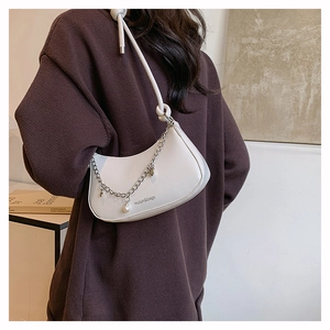 Detail of white hobo bag with silver chain, pearl heart charms and brand logo