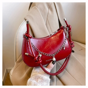 Detail of dark red crescent bag with knotted strap and decorative star pearl charms