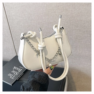 Detail of off-white crescent bag featuring rope handle, silver chain, and pearl charm