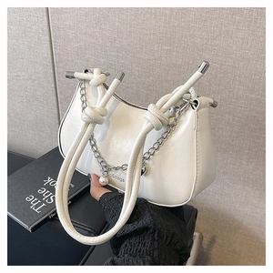 Detail of white glossy hobo bag with knotted tubular handles and pearl chain strap