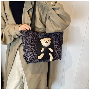 Detail of leopard print tote bag with 3D plush bear ornament and front black pocket