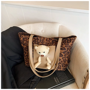Detail of leopard print tote bag with leather pocket and cute plush teddy bear insert