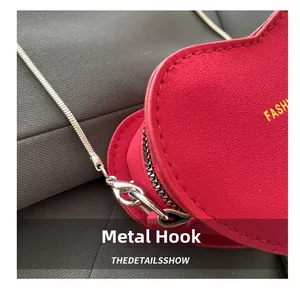 Detail of red heart-shaped mini bag showing silver metal hook and fine snake chain