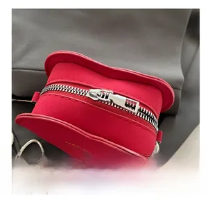 Close-up of red heart-shaped suede bag with silver zipper and fine metal chain strap