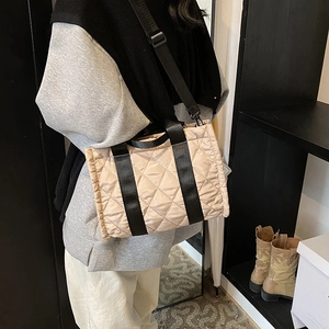 Elegante borsa tote trapuntata beige con cinghie nere indossata da una modella
