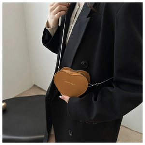 Vue détaillée d'un sac à bandoulière marron en forme de cœur avec lettrage doré