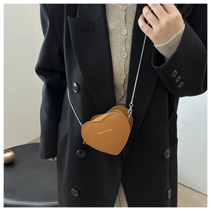 Brown heart-shaped mini crossbody bag with silver chain strap shown on a black suit blazer