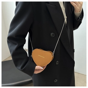 Close-up of heart-shaped mini crossbody bag in yellow leather with gold chain strap