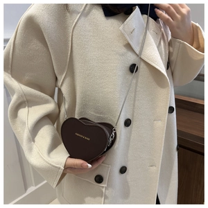 Détail d'un petit sac bandoulière marron en forme de cœur avec chaîne argentée chic