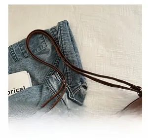 Close-up of vintage brown leather tote bag with slender straps and casual denim look
