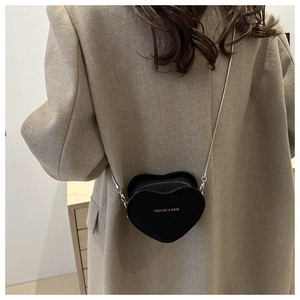 Détail d'un sac à bandoulière en forme de cœur avec chaîne argentée et logo doré