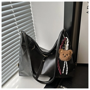 Detail of minimalist black hobo bag with teddy charm and woven strap accents