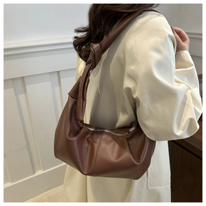 Macro detail of dark brown lychee textured leather and knotted shoulder strap of the bag