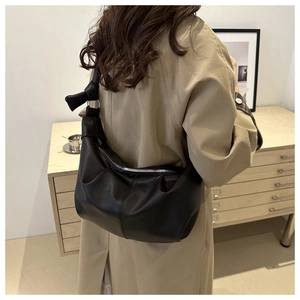 Close-up of black lychee grain leather hobo bag with unique knotted strap detail