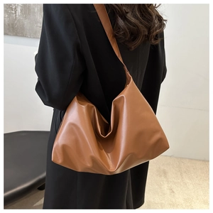 Gros plan d'un sac hobo en cuir PU marron avec large bandoulière sur un costume noir