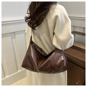 Détail du sac hobo marron café porté à l'épaule avec texture en cuir lisse