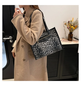 Detailed shot of a stylish leopard print tote bag with black straps on a female model