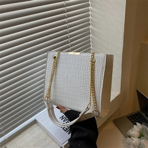 Chic white crocodile pattern tote bag with gold chain strap in a modern office setting