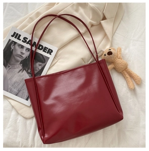 Detail of the dark red PU leather tote bag with slim shoulder straps in a lifestyle setting