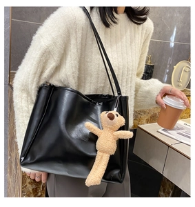Detail of black large capacity tote bag featuring a cute beige plush bear charm accessory