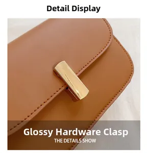 Close-up of a glossy gold hardware clasp on a caramel brown leather crossbody bag
