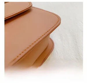 Detailed close-up showing precision stitching on the brown leather crossbody bag
