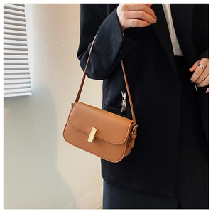 Close-up of a brown rectangle shoulder bag with a gold metal buckle on a black blazer