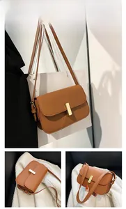 Detail view of brown PU leather shoulder bag with golden metal buckle and smooth oil edges