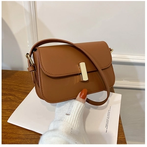 Close-up of retro brown crossbody bag featuring a sleek gold metal bar lock and textured leather
