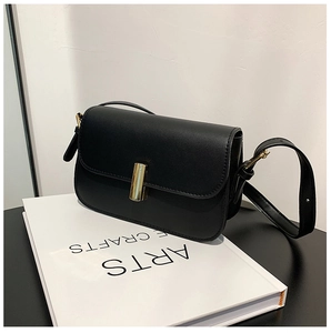 Minimalist black leather crossbody bag with premium gold bar clasp on white books