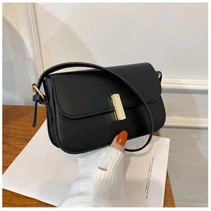 Detail of minimalist black PU leather crossbody bag with golden rectangular turn-lock closure