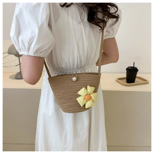 Detail of woven beach bag with yellow floral motif and elegant pearl buckle closure