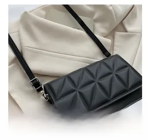 Détail de la texture géométrique matelassée noire mate et des ferrures argentées du sac