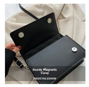 Détail du sac bandoulière noir montrant la fermeture à double boucle magnétique