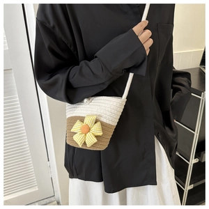 Detail of small woven crossbody bag with sun flower decor and pearl button closure