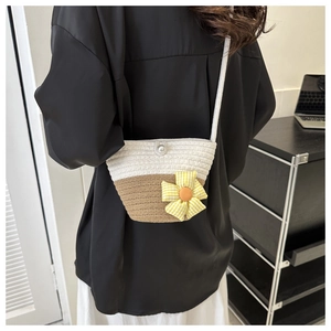 Close-up of woven straw crossbody bag with pearl button and checkered fabric flower