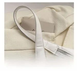 Detail view of durable top handles and fine stitching on a white faux leather tote bag