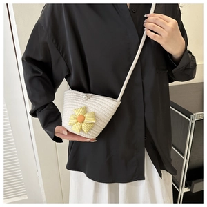 Close-up of a white woven shoulder bag with a yellow plaid flower and pearl button