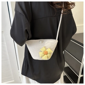 Close-up of a mini woven crossbody bag featuring a yellow cloth flower and pearl button