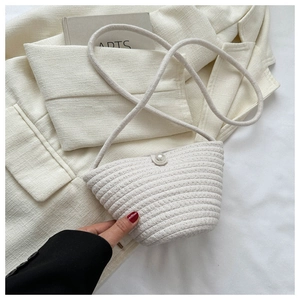 Detail of hand-woven beige bucket bag featuring a large pearl clasp and rope strap