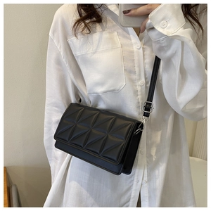Modèle portant un sac bandoulière noir matelassé avec motifs géométriques et fermoir