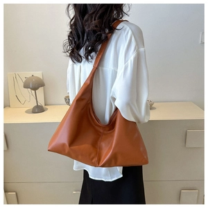 Detailed view of caramel brown faux leather shoulder bag with wide strap and soft texture