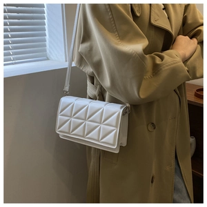 Gros plan d'un sac bandoulière blanc avec motifs géométriques 3D porté par un mannequin