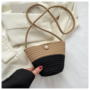 Detail of hand-woven bucket bag with contrast trim and decorative pearl clasp closure