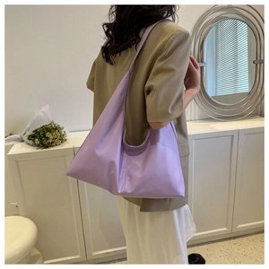 Detail of light purple Hobo shoulder bag shown with khaki blazer and white dress