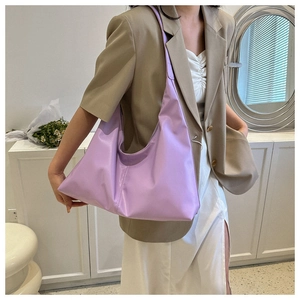 Detailed close-up of a soft lavender faux leather shoulder bag worn with a brown blazer
