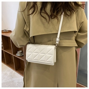 Détail d'un petit sac bandoulière blanc matelassé avec motif géométrique sur trench